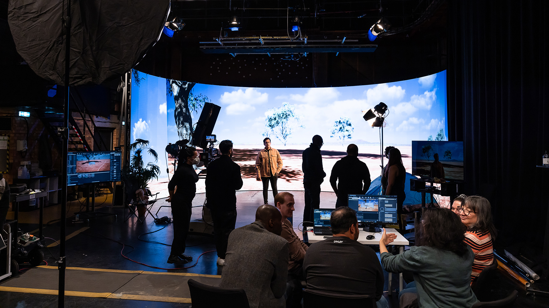 people working on set in front of large virtual production screen