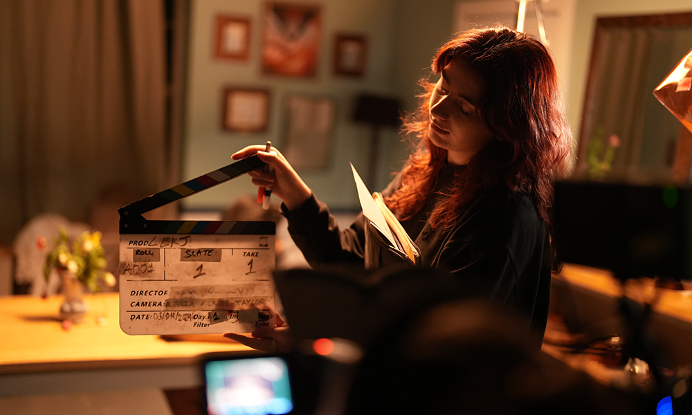 A young filmmaker marks the next film scene with a clapperboard