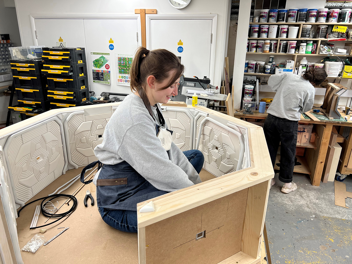 A model maker inside the 1:5 scale chamber, making adjustments to the curved pipes surrounding each section of the octagon.